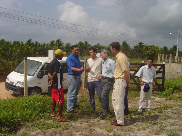 a group of people standing around outside near a fence