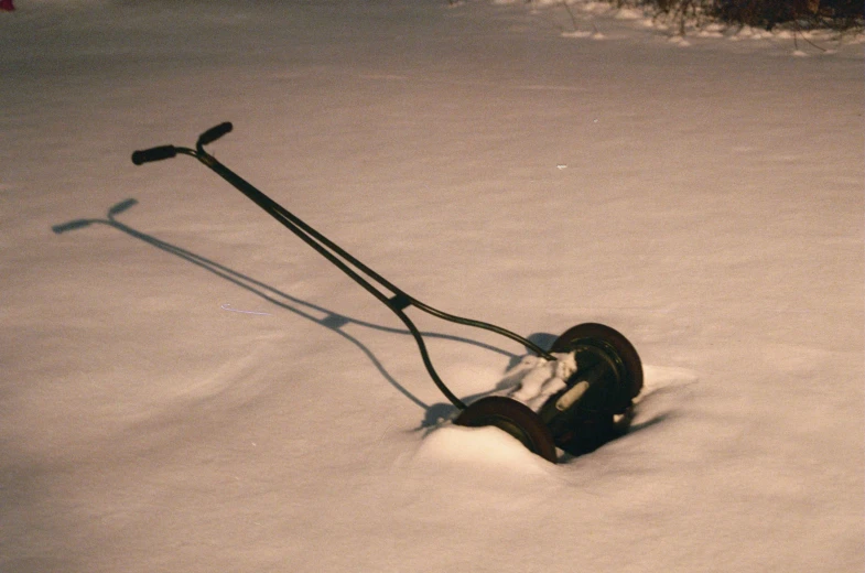 an old mower with a handle and a harness sitting in the snow