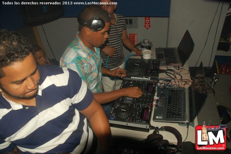 three young men at a mixing station are working on the music