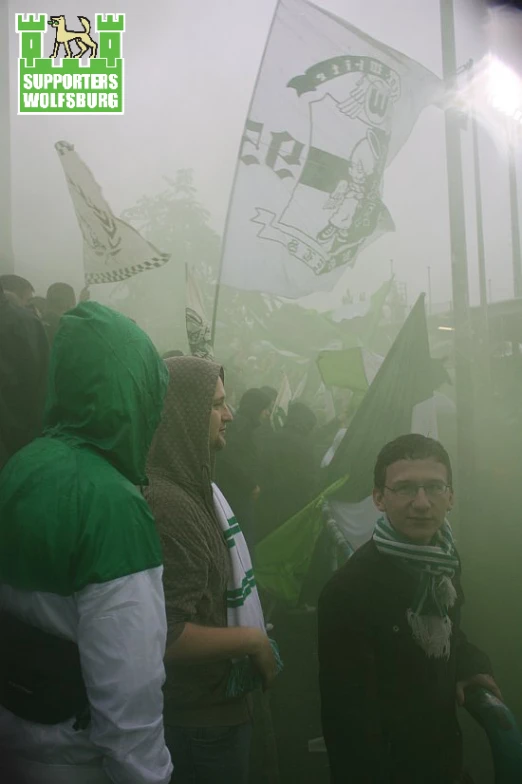 a group of people standing on top of a street covered in green flags