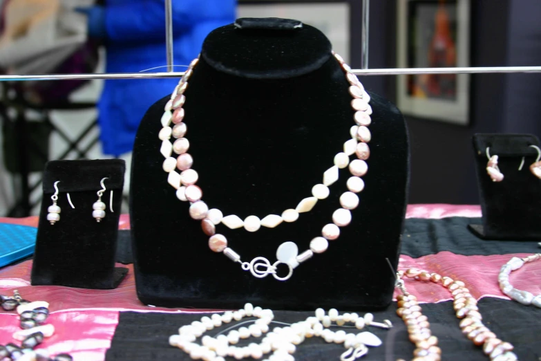 two white pearl necklaces and two necklace earrings on display