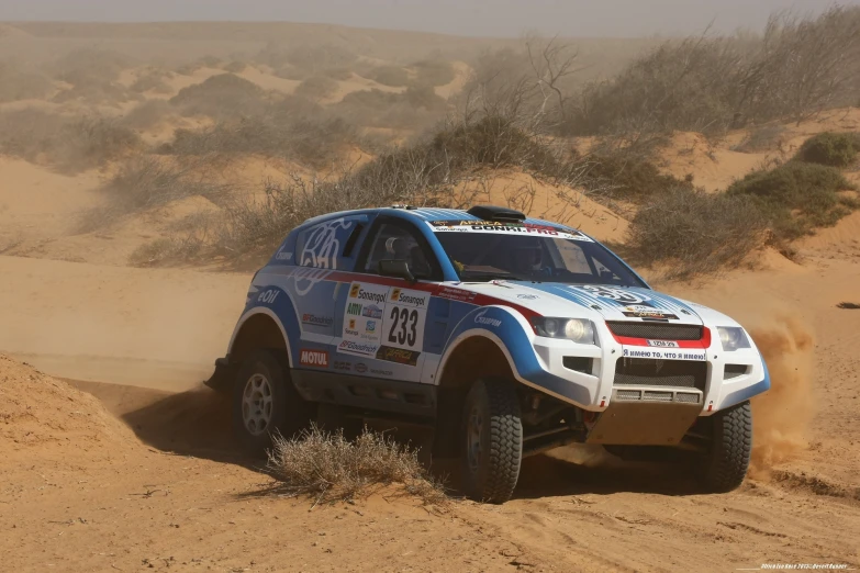 a blue truck making it's way across sand dunes