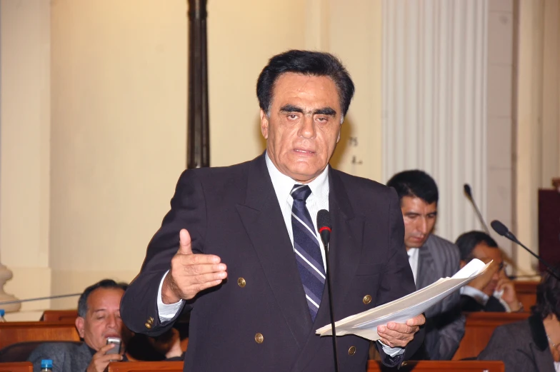 a man holding a newspaper and giving a speech