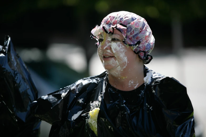 a woman wearing plastic wraps on her head and a towel wrapped around her hair, laughing