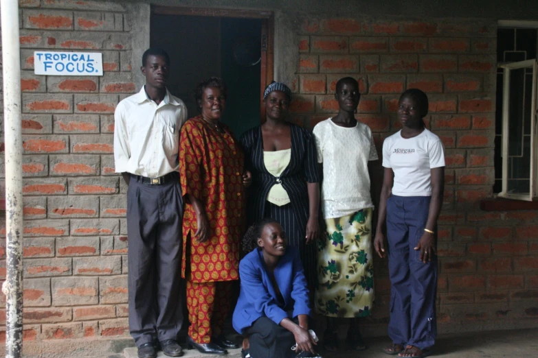 a group of women standing next to each other in front of a brick building