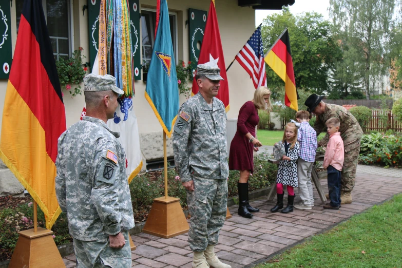 soldiers stand in front of flags with children