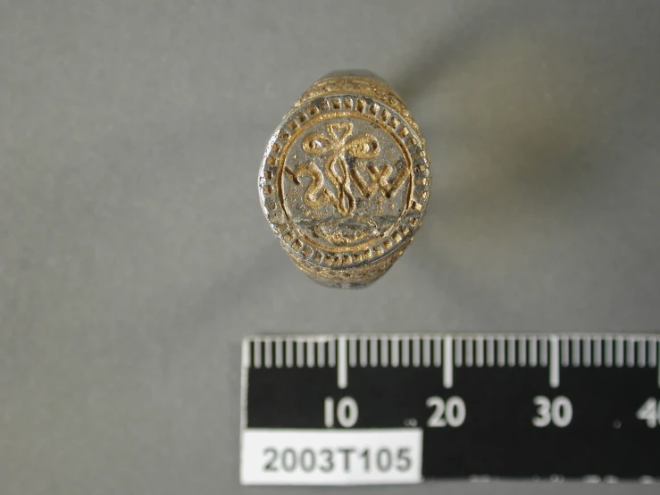 a small gold badge and a ruler on a table