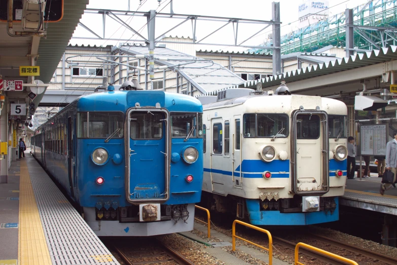 two passenger trains on the tracks in an empty train station