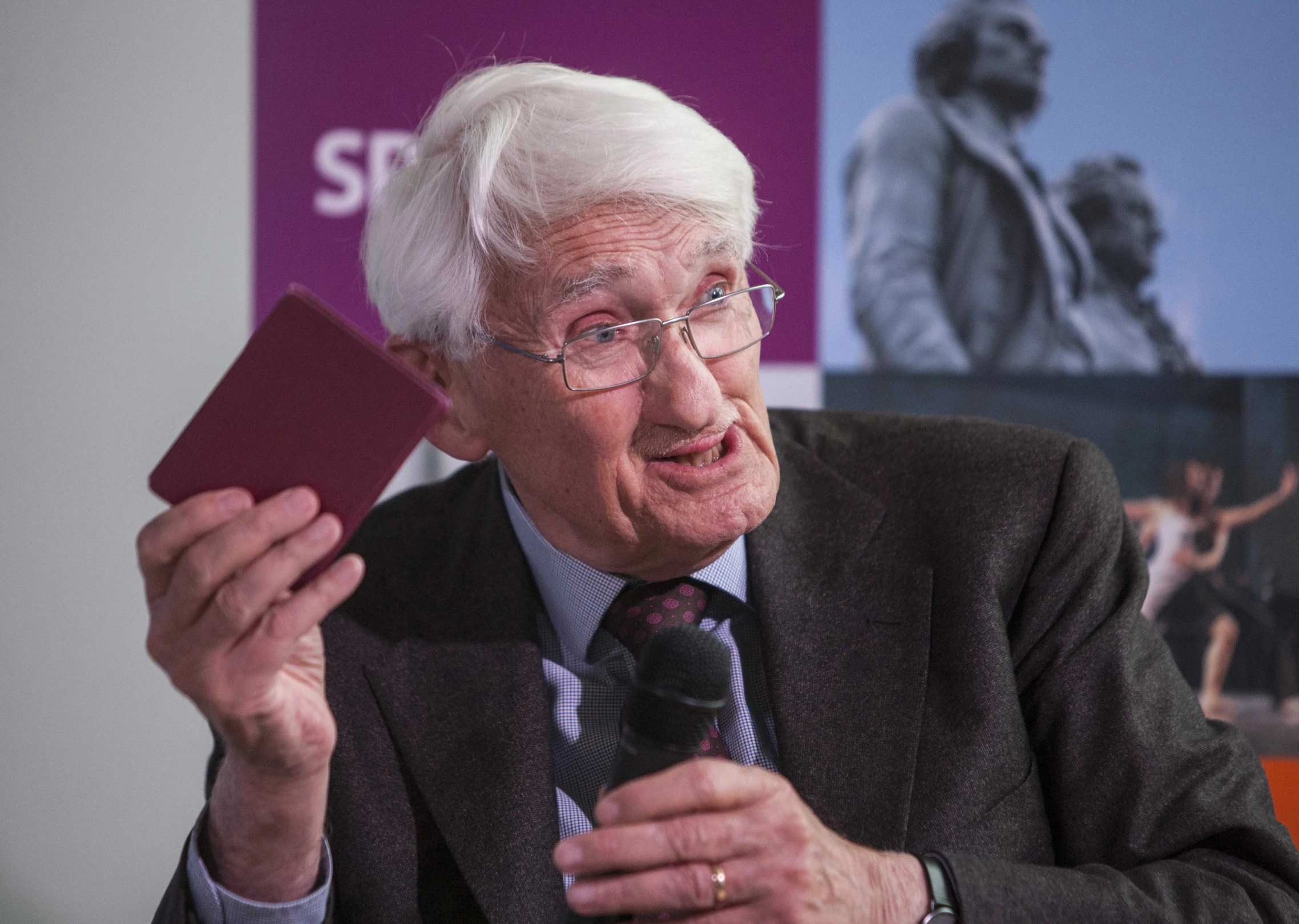 an older man holding a maroon box in his hand