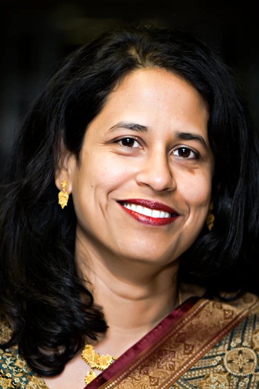 a smiling woman dressed in an ethnic indian outfit