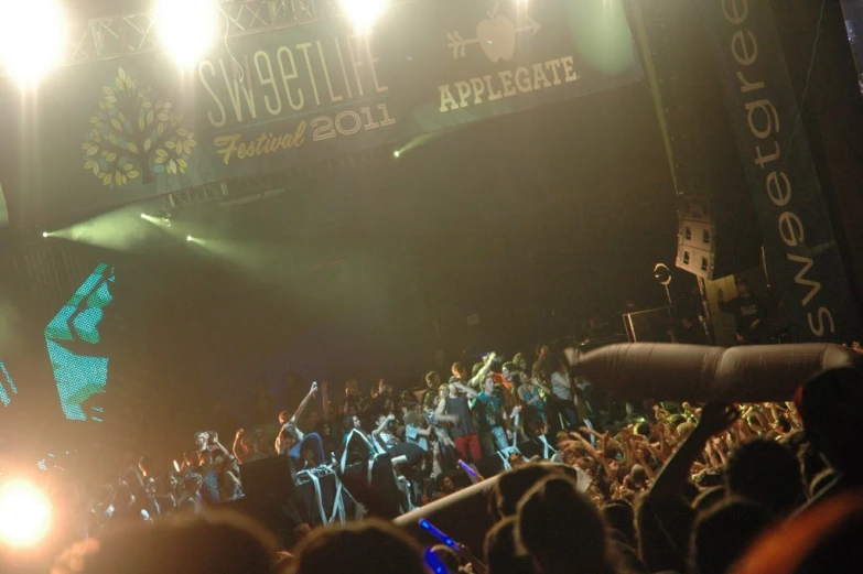 a crowd of people standing on a stage in front of a stage with lights