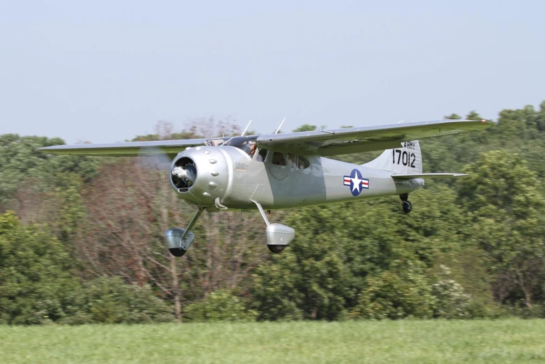 an airplane with propeller and four propellers taking off from a field