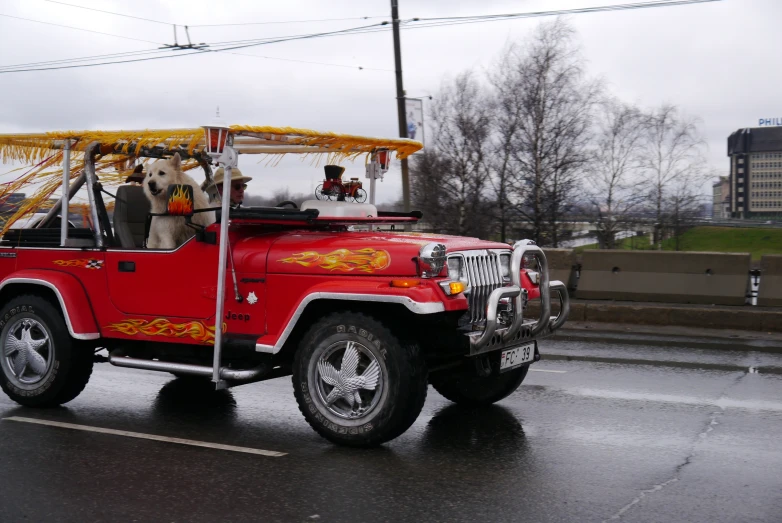 a red jeep is on the road with a canopy