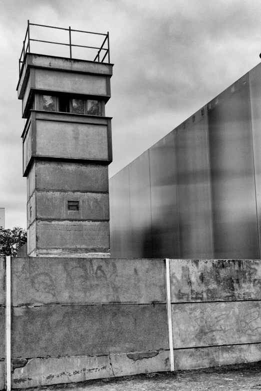 a man walking along side a fence next to a tall building