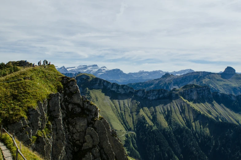 three hikers are standing on a mountain top near some mountains