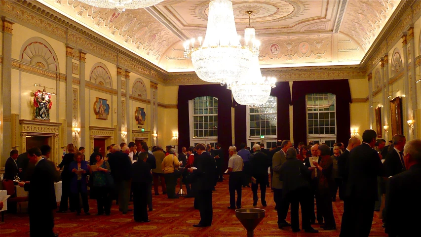 a crowd of people walking through a lobby with ornate walls and ceilings