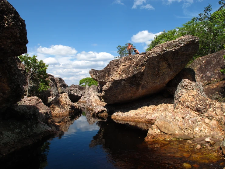 the person is sitting on the rocks by the river