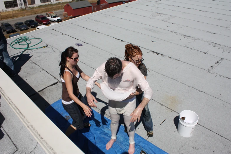 three women in a row stand on the edge of a roof