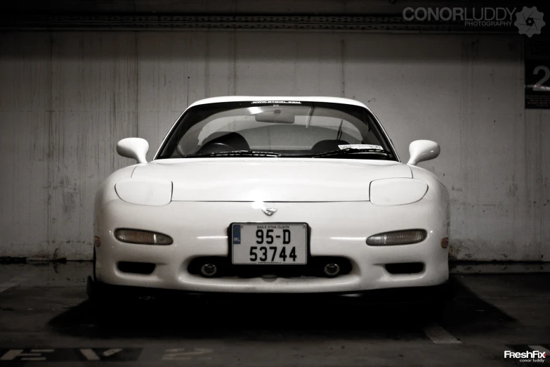 white sports car in parking space with number plate