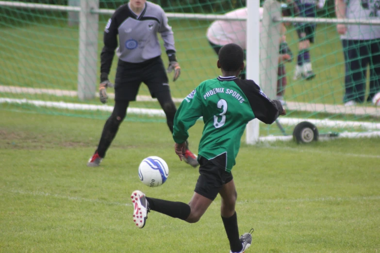 the soccer player has just jumped his foot toward the ball