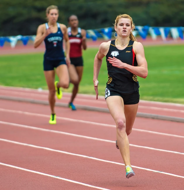 three girls are running around the track in a race