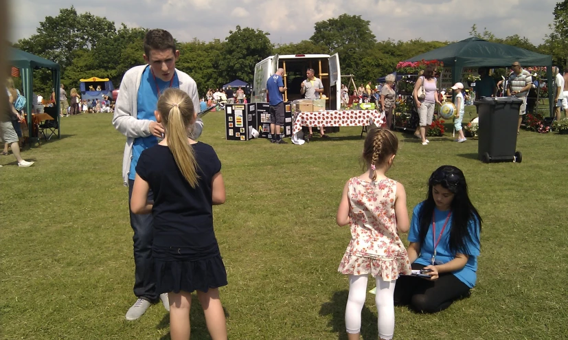 children are gathered around a man on a cell phone