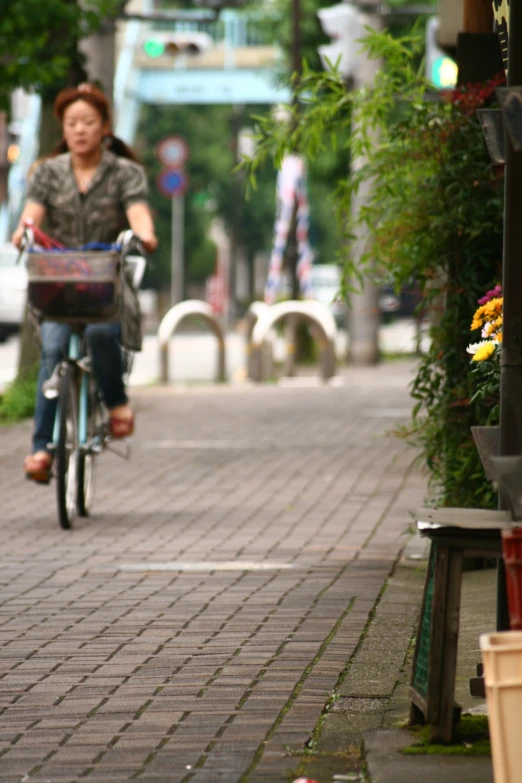 woman riding bike on brick path past bushes