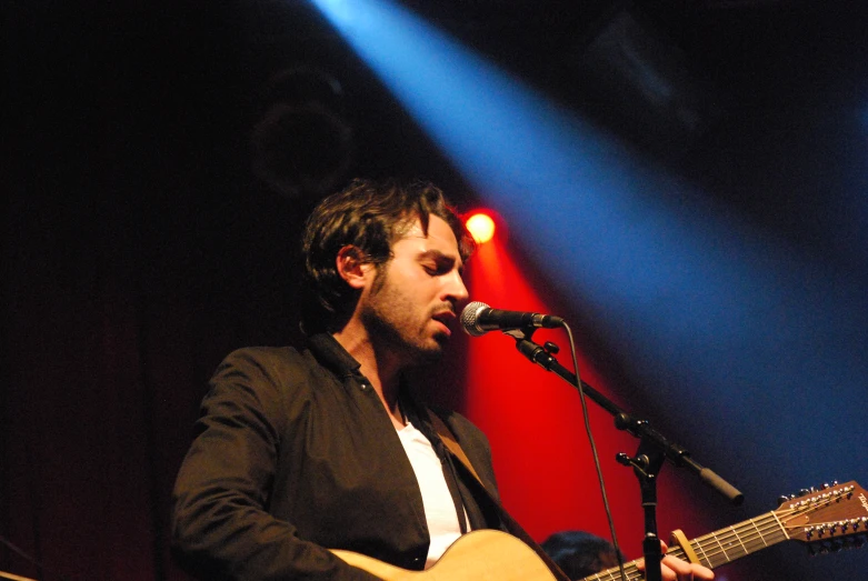 man with guitar at a microphone playing it