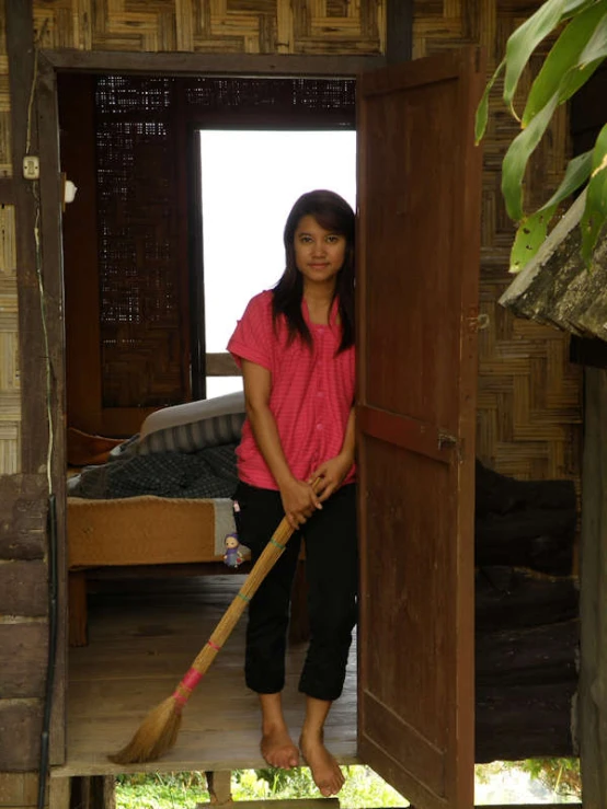 a woman in pink shirt holding a broom near wooden steps