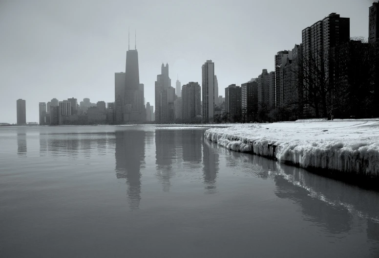 snow covers the ground and water in front of a city