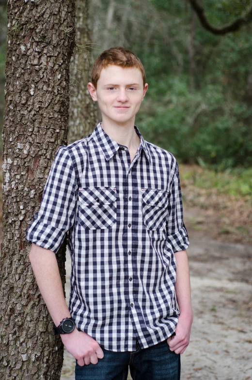 man in plaid shirt standing next to tree with black and white pattern