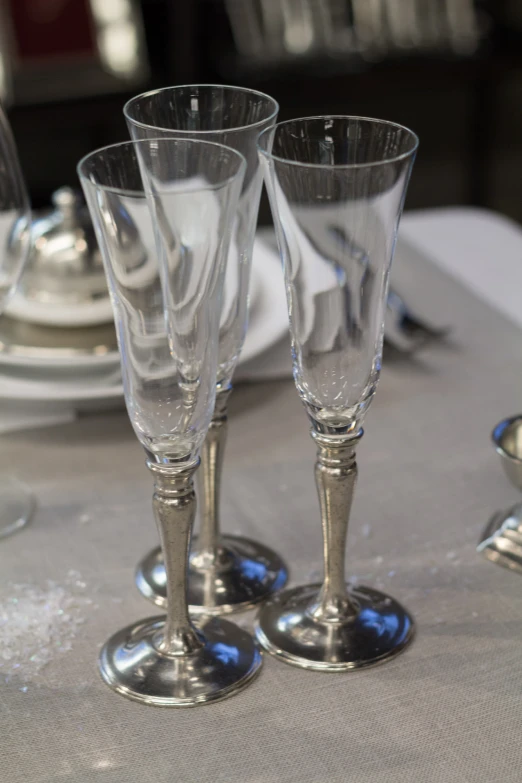 an arrangement of four clear wine goblets on a table