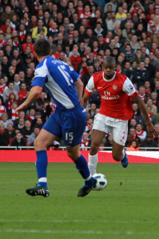 two men kicking a soccer ball while people watch