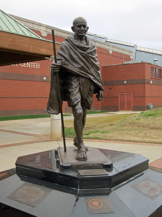 a bronze statue of a person with a sceptet on a park bench