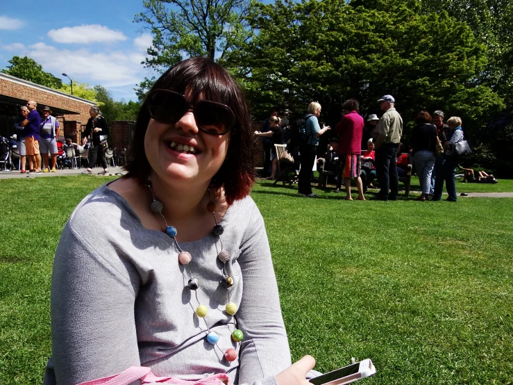 a woman smiles while sitting in the grass