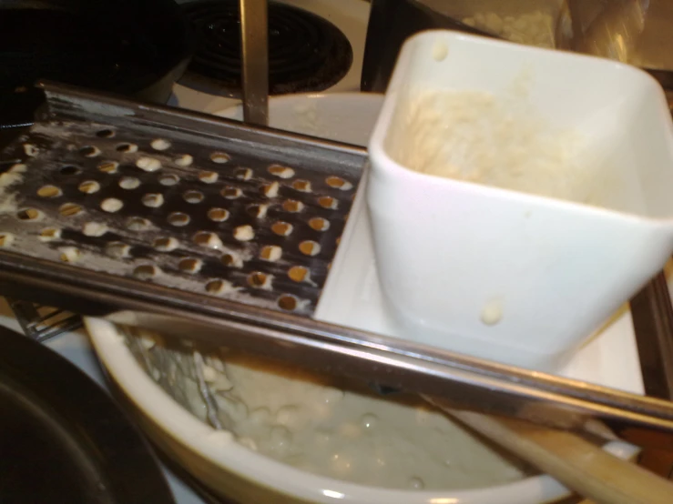 a dirty toilet sits next to a cup and strainer