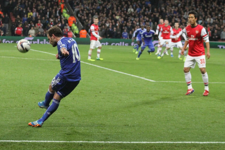 a soccer player kicking a soccer ball while a crowd watches