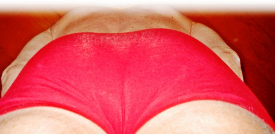a woman in red underwear laying on a wooden floor