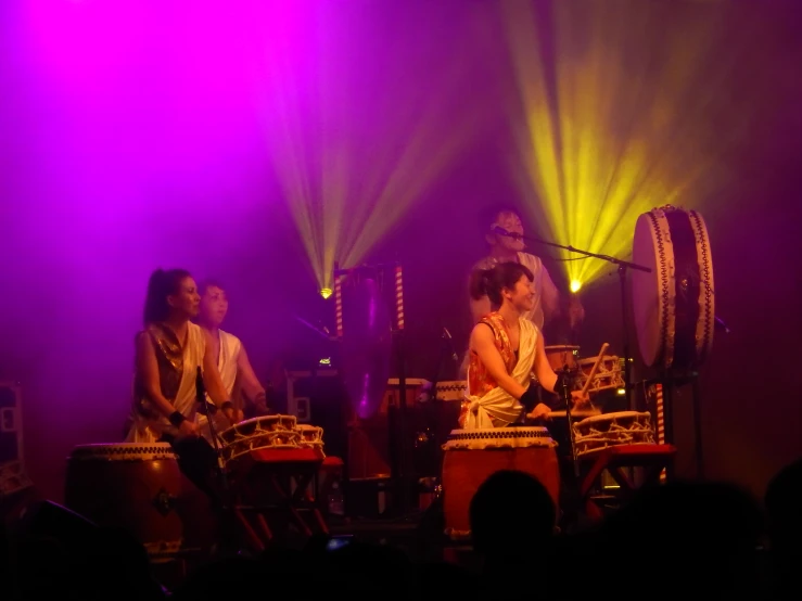 several people standing on stage with instruments and lights behind them