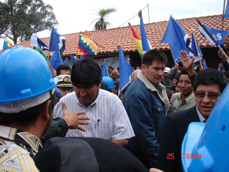 man with hard hat standing next to people and flags