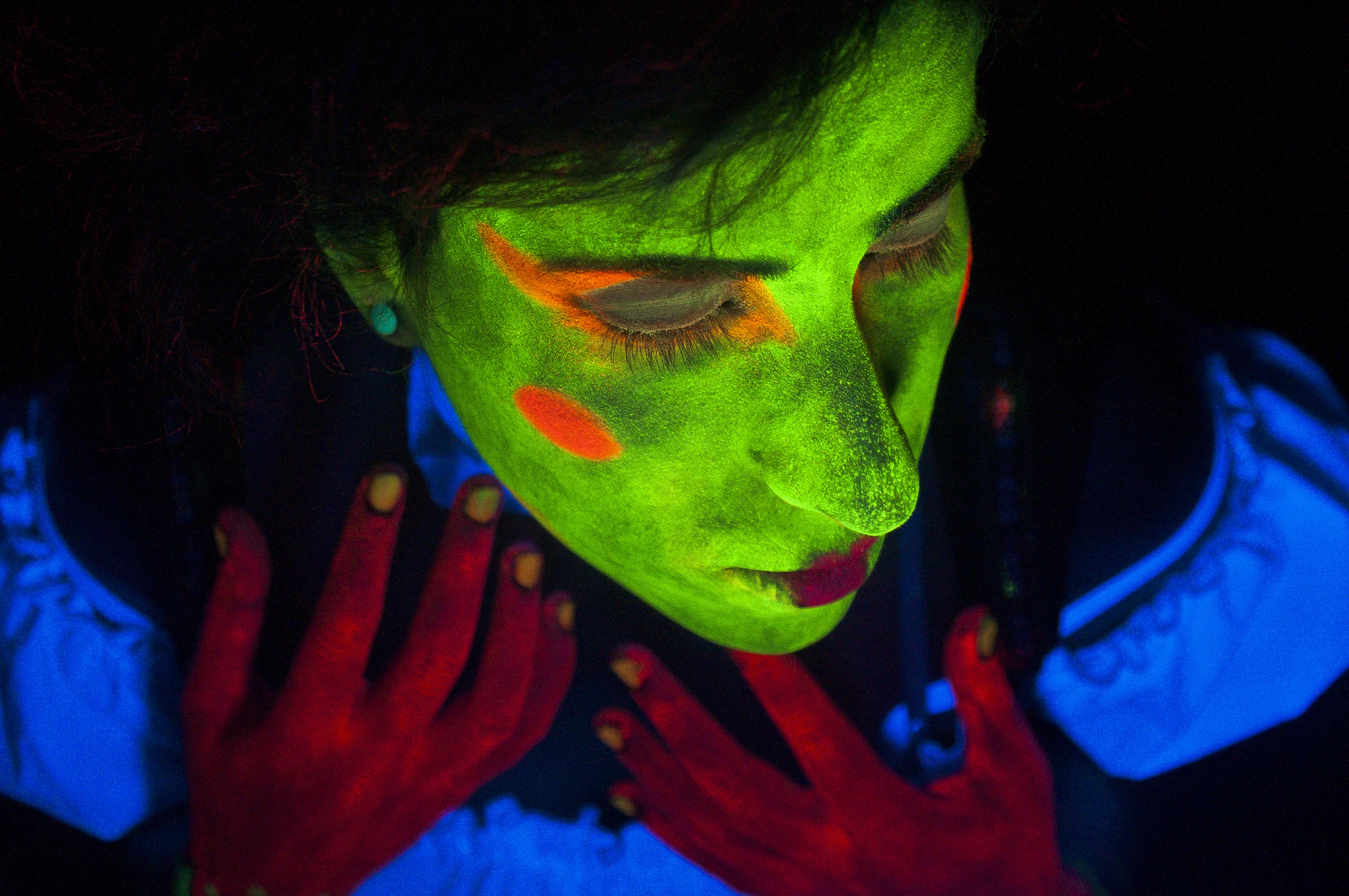 a young man with face paint and neon painted hands