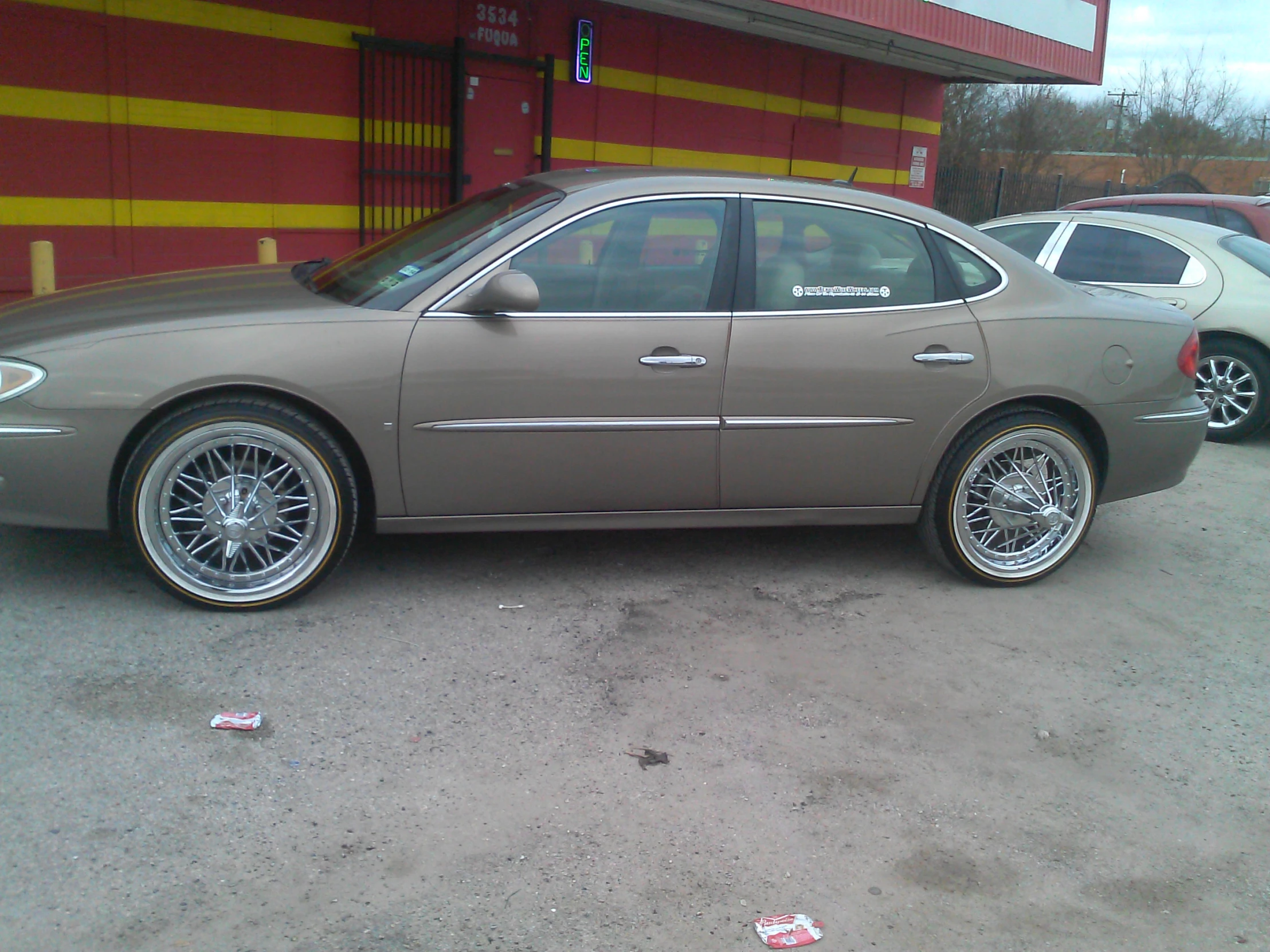 a metallic car in parking lot next to building