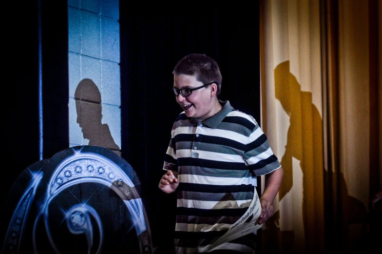 a man standing by a dark stage lighting, smoking a pipe