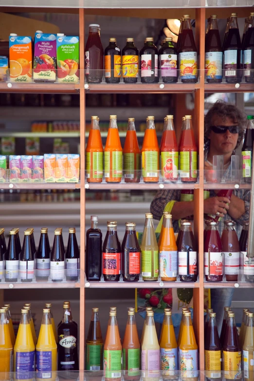 a woman standing behind a display shelf filled with bottles of juice