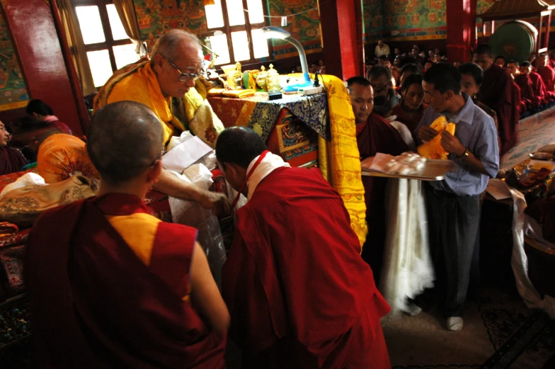 monks stand in a large room while one man sits at the table