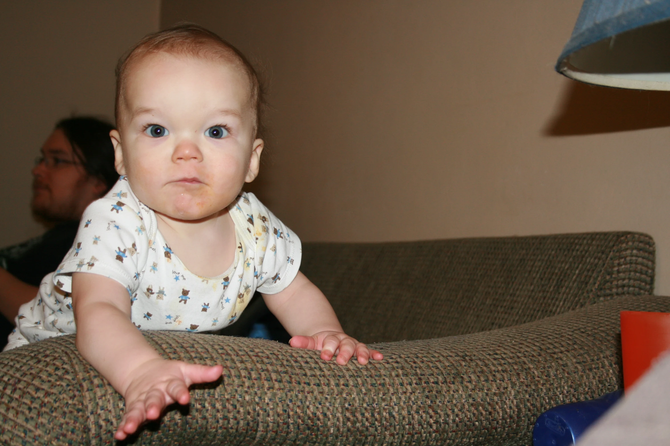 a baby sitting on a brown couch looking off in the distance