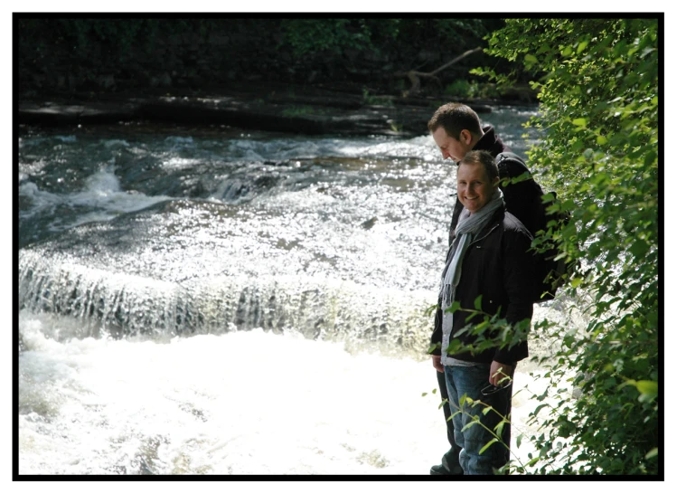 two men are standing next to a large waterfall