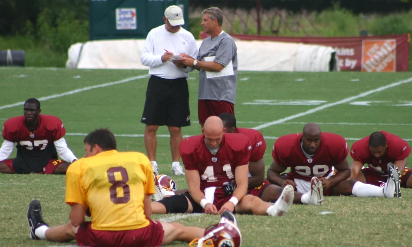 some american football players on a field and two coaches