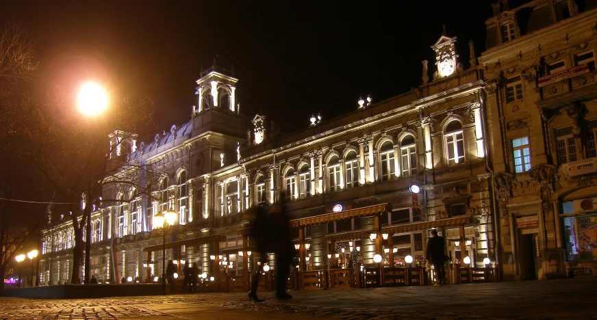 an old building with many windows and some lit up street lamps