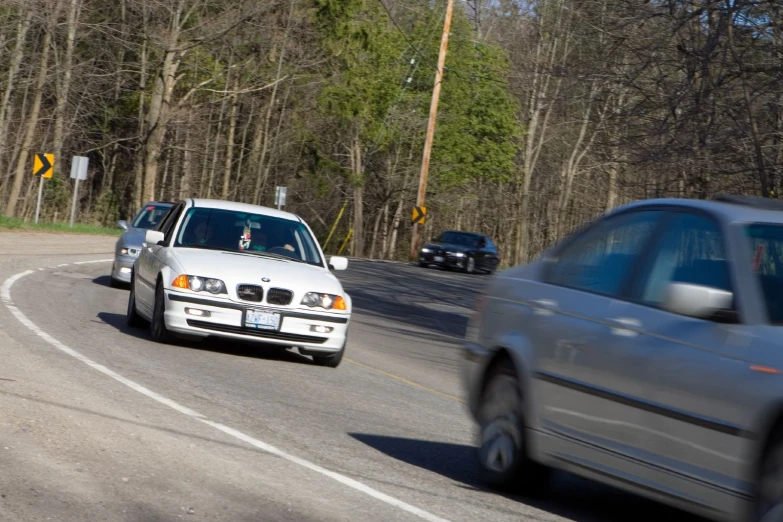 some cars driving on the road near some trees